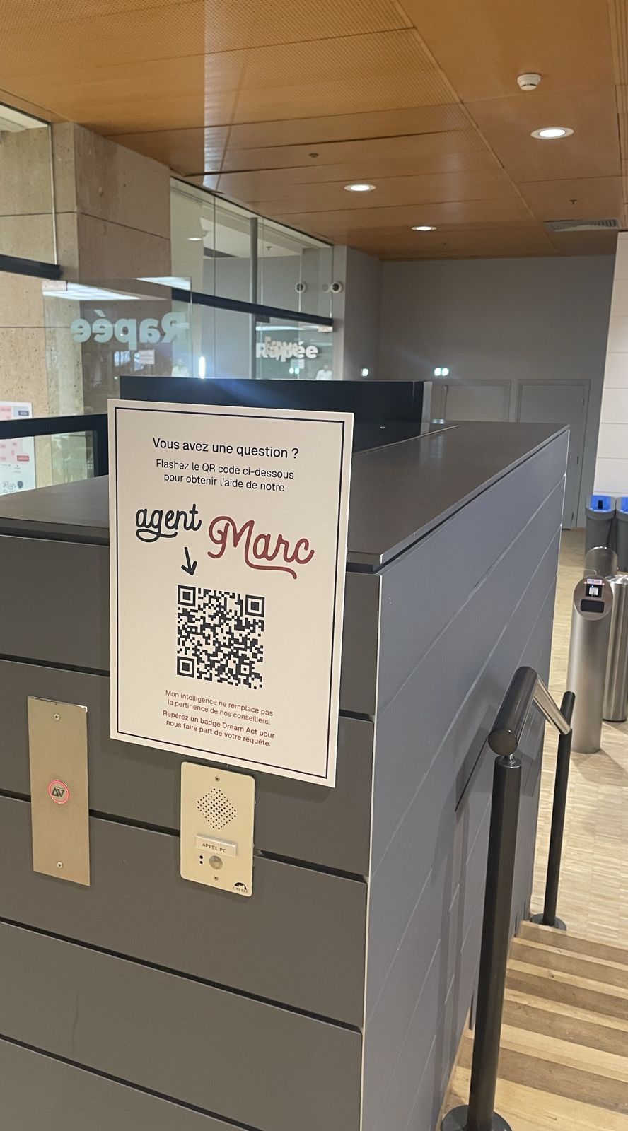Affiche avec le QR code de l'agent Marc, posée sur un comptoir d'accueil